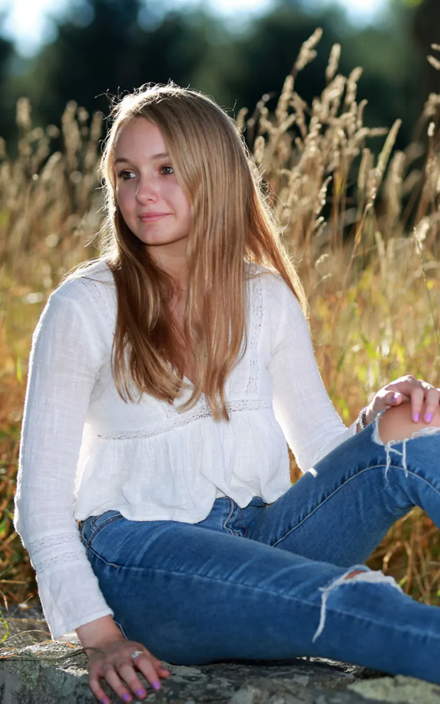 A young woman sitting on a rock in tall golden grass