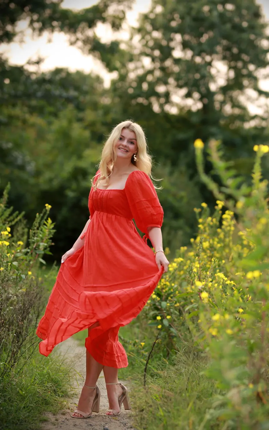A young woman in a flowing red dress in a summer meadow