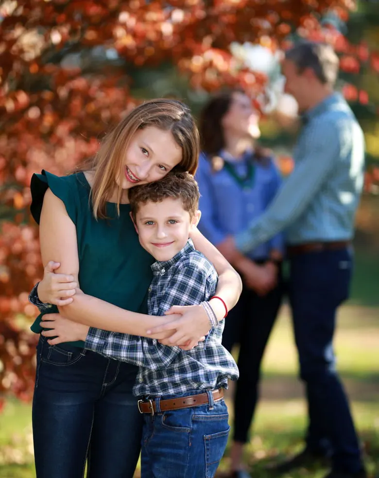 A mother and son hugging in front of autumn trees